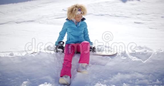 美丽的年轻滑雪者坐在雪地上视频的预览图