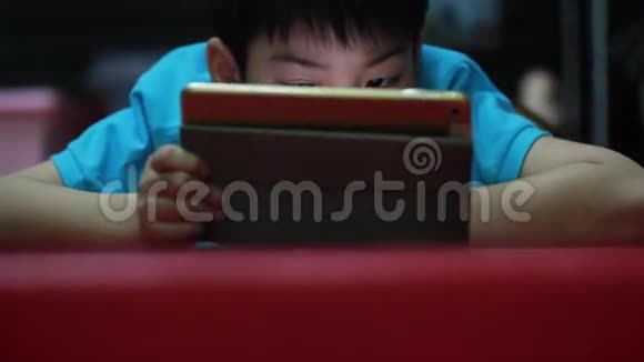 小亚裔男孩玩平板电脑游戏视频的预览图