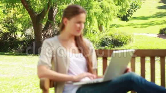 在长凳上用笔记本电脑的女人视频的预览图