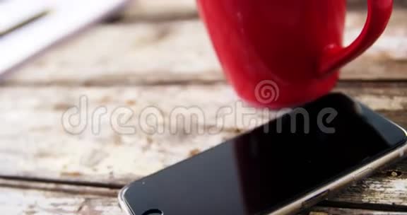 木制木板上的咖啡杯和手机视频的预览图