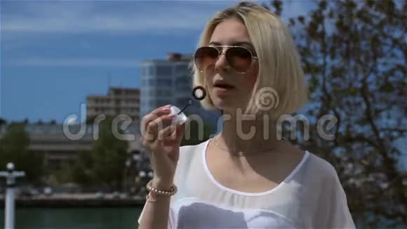 年轻迷人的女孩戴着太阳镜吹泡泡视频的预览图