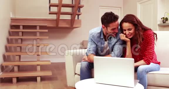 快乐夫妻在沙发上用笔记本电脑视频的预览图