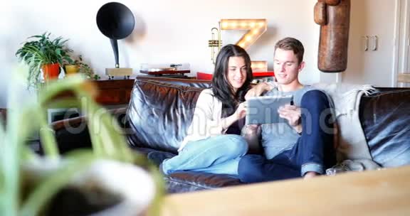 客厅里的情侣用数码平板电脑视频的预览图
