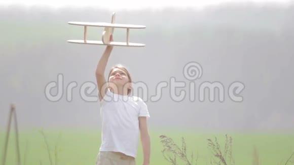 白人男孩玩模型飞机一个在田野里坐木飞机的孩子的肖像视频的预览图