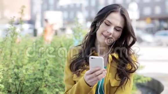 带着智能手机和耳机的快乐年轻女人视频的预览图