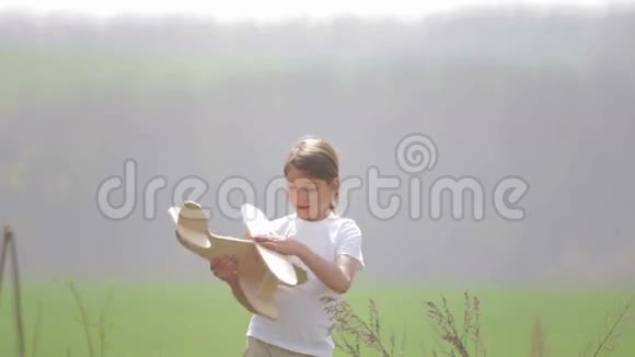 白人男孩玩模型飞机一个在田野里坐木飞机的孩子的肖像视频的预览图