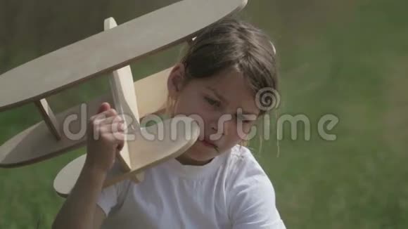 白人男孩玩模型飞机一个在田野里坐木飞机的孩子的肖像视频的预览图