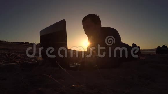 手提电脑商人自由职业者手提电脑工作在沙滩上自由职业者在阳光下的剪影视频的预览图
