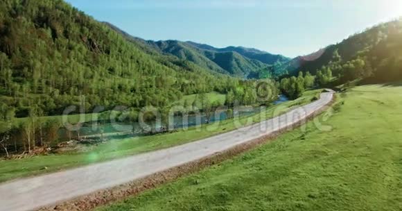 超高清4K鸟瞰图在阳光明媚的夏季早晨低飞过新鲜寒冷的山河草地和道路视频的预览图