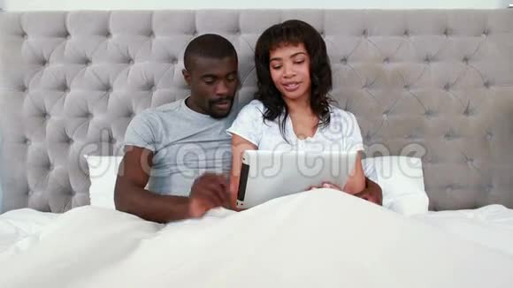 一对夫妇在床上一起用平板电脑视频的预览图