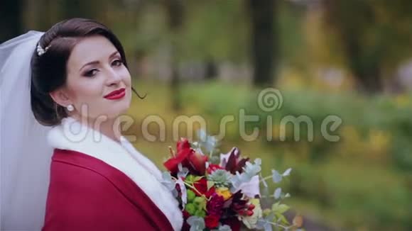 美丽的新娘带着婚礼花束在公园里视频的预览图