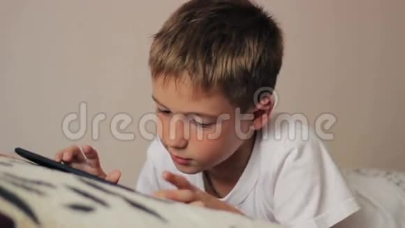 漂亮的小男孩在平板电脑上玩视频的预览图