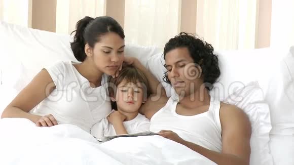 年轻的家庭在床上看书视频的预览图