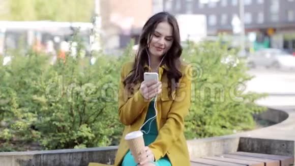 带着智能手机和耳机的快乐年轻女人视频的预览图