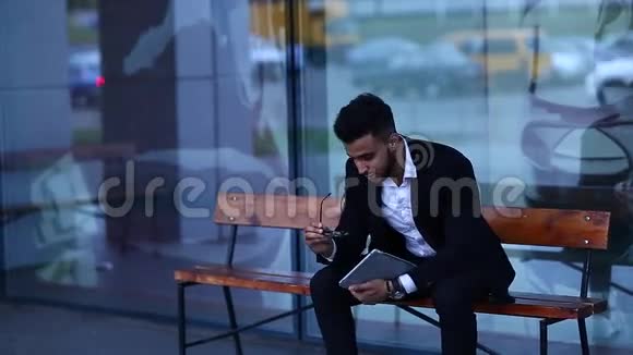 穿西装的阿拉伯男人在商务中心附近戴上带有平板电脑的太阳镜视频的预览图