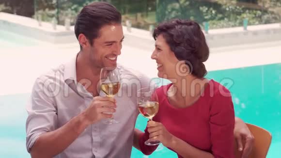 微笑的夫妇喝着酒池边视频的预览图