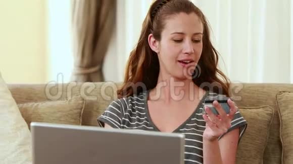 在笔记本电脑上打字时拿着信用卡的女人视频的预览图