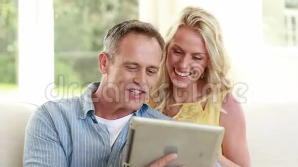 幸福夫妇在沙发上用平板电脑视频的预览图