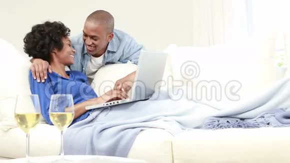 有魅力的情侣在沙发上用笔记本电脑视频的预览图