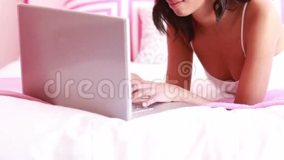有魅力的女人用笔记本电脑躺在床上视频的预览图