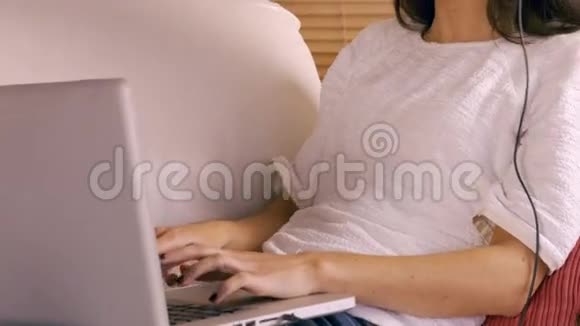 微笑的女人在沙发上用笔记本电脑视频的预览图