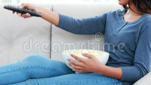 女人一边吃爆米花一边在沙发上放松视频的预览图