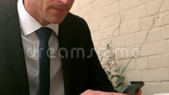 英俊的商人用他的智能手机视频的预览图