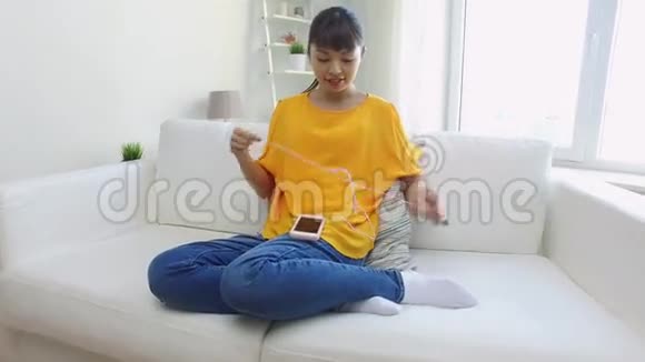 带智能手机和耳机的快乐亚洲女人视频的预览图