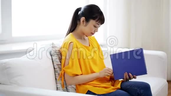 微笑着年轻的亚洲女人在家看书视频的预览图