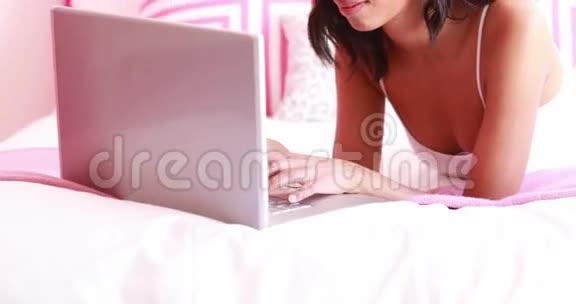 有魅力的女人用笔记本电脑躺在床上视频的预览图