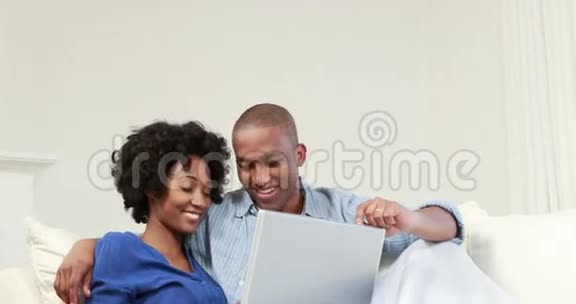 有魅力的情侣在沙发上用笔记本电脑视频的预览图