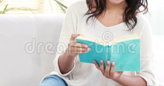 微笑的女人在沙发上看书视频的预览图