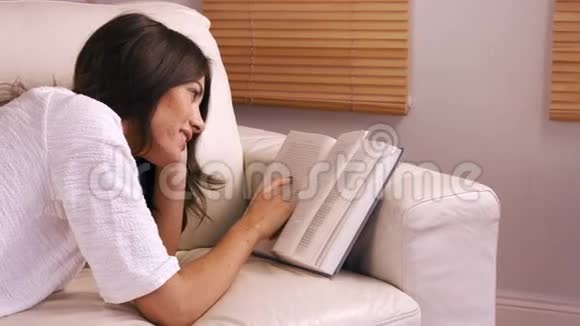 微笑的女人在沙发上看书视频的预览图