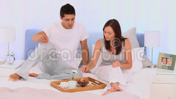 一对在床上吃早餐的夫妇视频的预览图