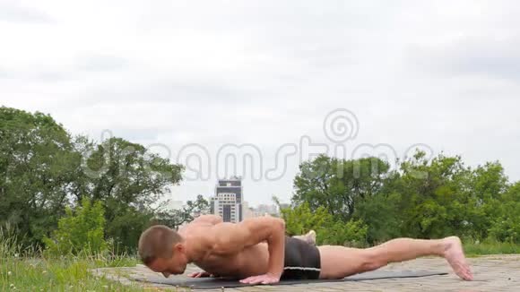 在公园里做瑜伽的英俊灵活的运动员视频的预览图