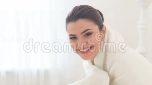 年轻微笑的女人坐在床上视频的预览图