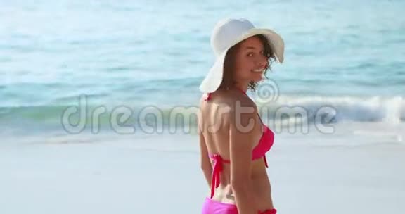 在海滩上对着镜头微笑的深褐色美女视频的预览图