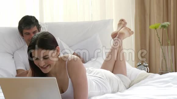 女人用笔记本电脑男人在床上看书视频的预览图