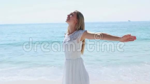 快乐的金发女人双臂伸向海滩视频的预览图