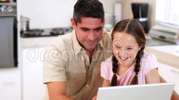 父亲和女儿用笔记本电脑视频的预览图
