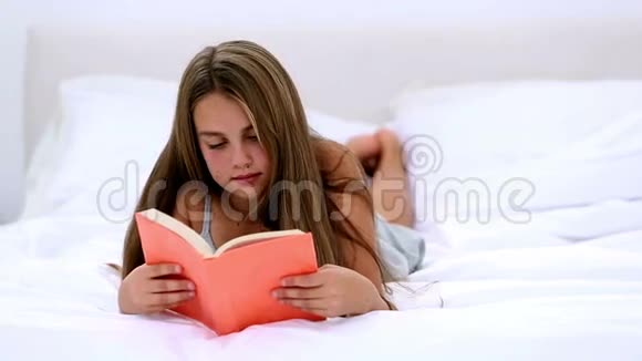 可爱的女孩躺在床上看书视频的预览图
