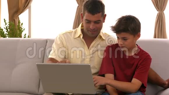父子俩在沙发上用笔记本电脑视频的预览图