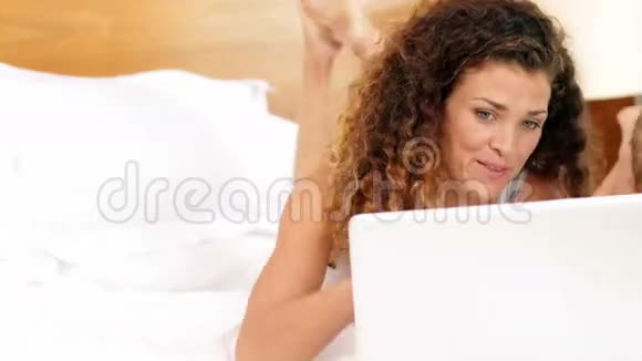 母亲和儿子在床上使用笔记本电脑视频的预览图