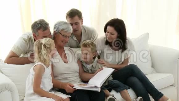 一家人坐在沙发上看一本相册视频的预览图