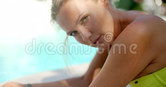 泳池边的金发女人在镜头前微笑视频的预览图