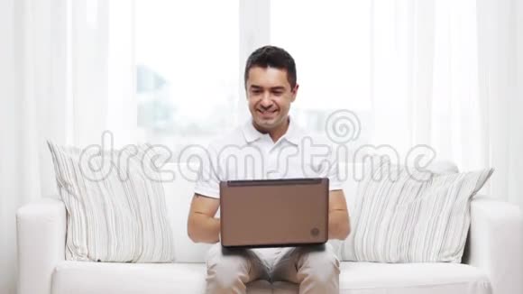 快乐的男人在家里用笔记本电脑工作视频的预览图