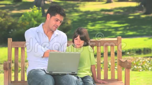 父亲和儿子带着笔记本电脑在户外视频的预览图