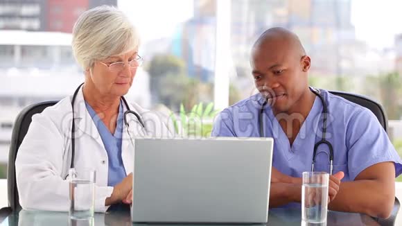 一个医生和一个护士在看手提电脑视频的预览图