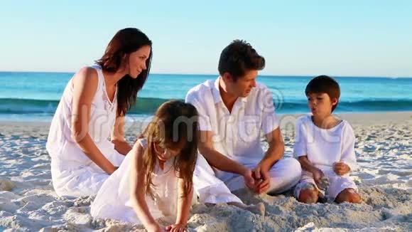 快乐的家庭坐在沙滩上视频的预览图