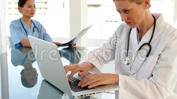 微笑医生用笔记本电脑坐在桌子旁视频的预览图